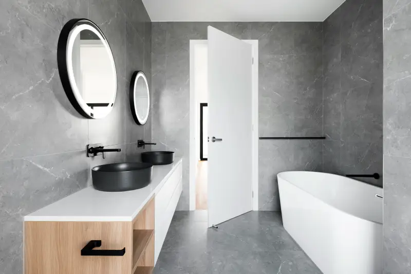 bagno stile moderno piastrelle grigie, dettagli neri e inserti in legno chiaro
